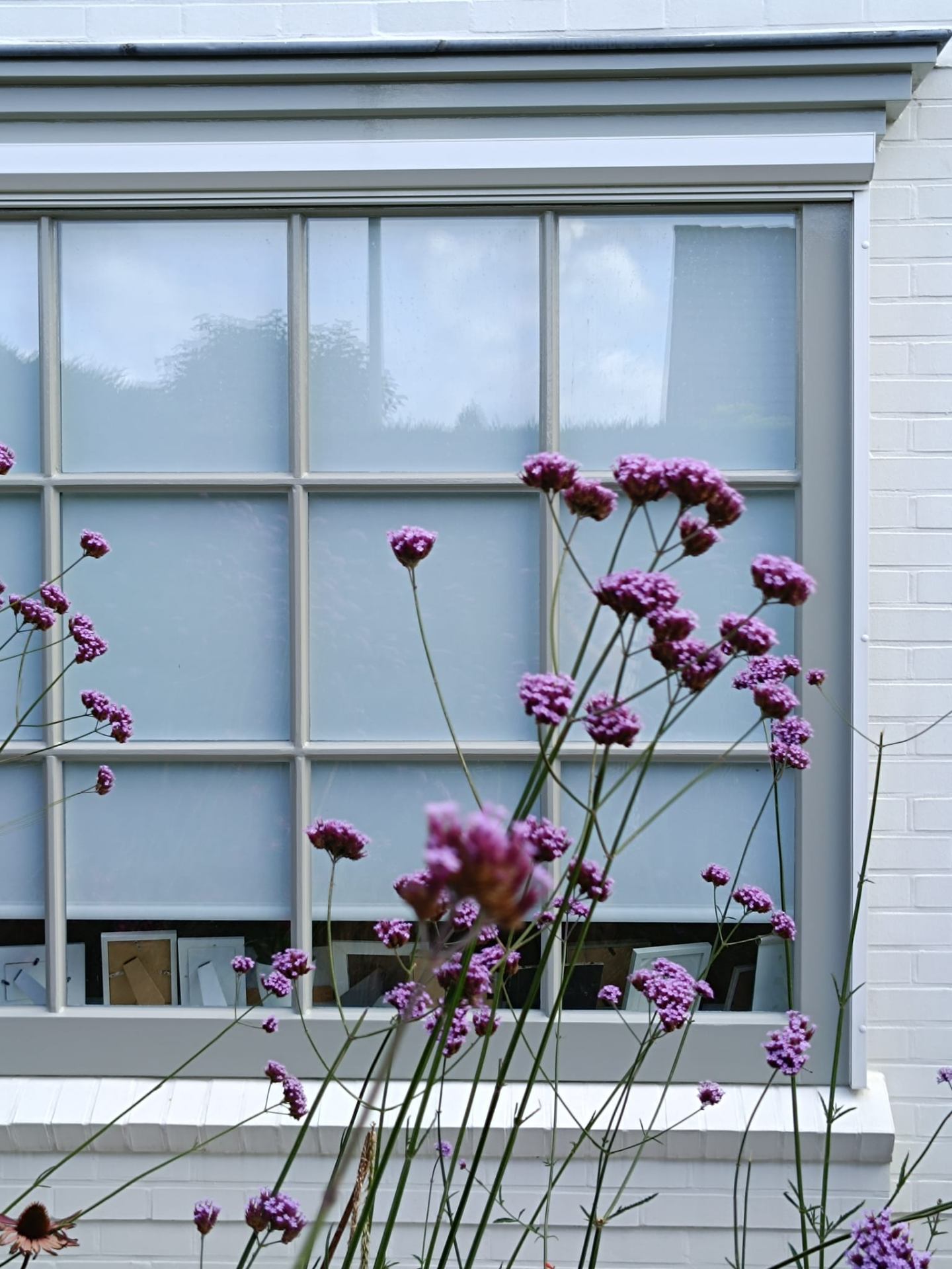 Wit geschilderde gevel met klassiek raamwerk en bloemen