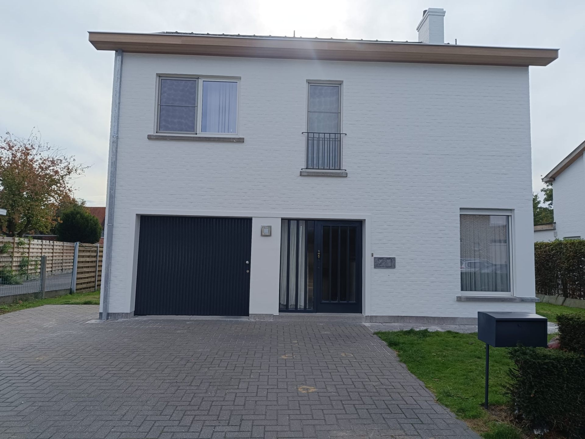 Wit geschilderde gevel met garagepoort en voordeur