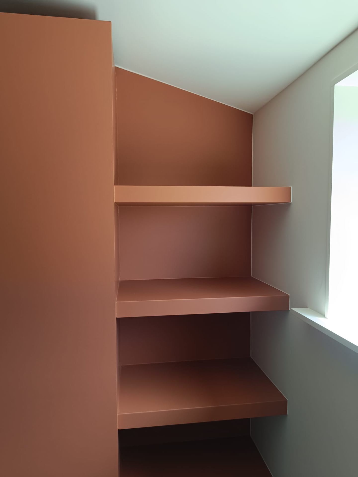Ingebouwde kast met terracotta kleurige rekken