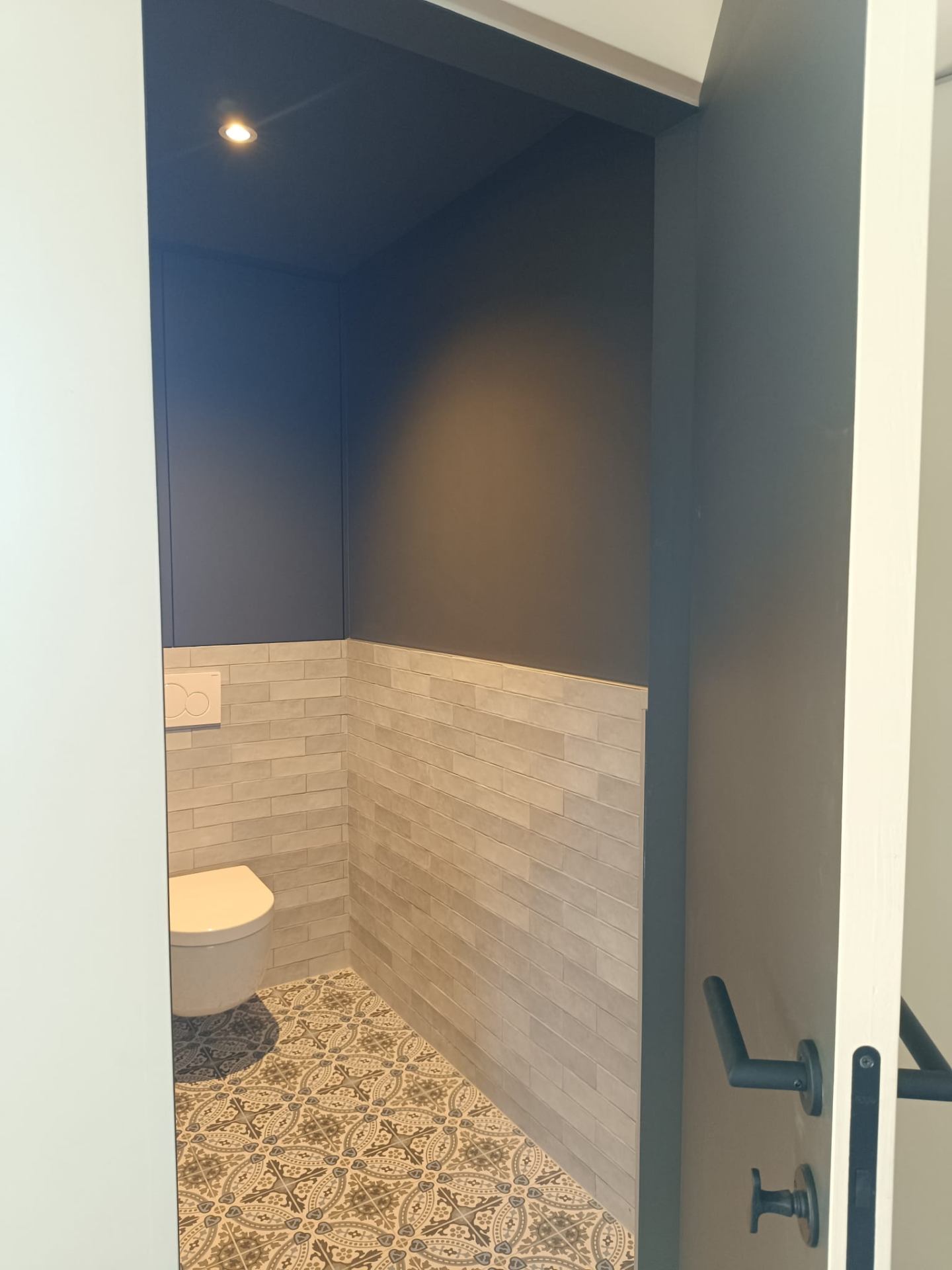 Toilet met donkerblauwe wand en decoratieve tegelvloer