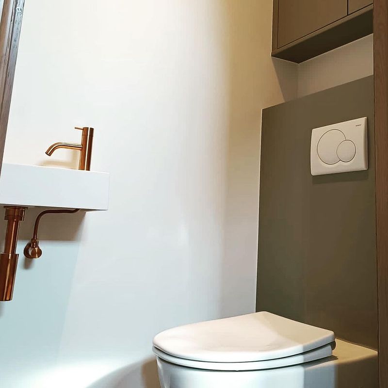 Toilet met koperen accenten en donkere wandafwerking