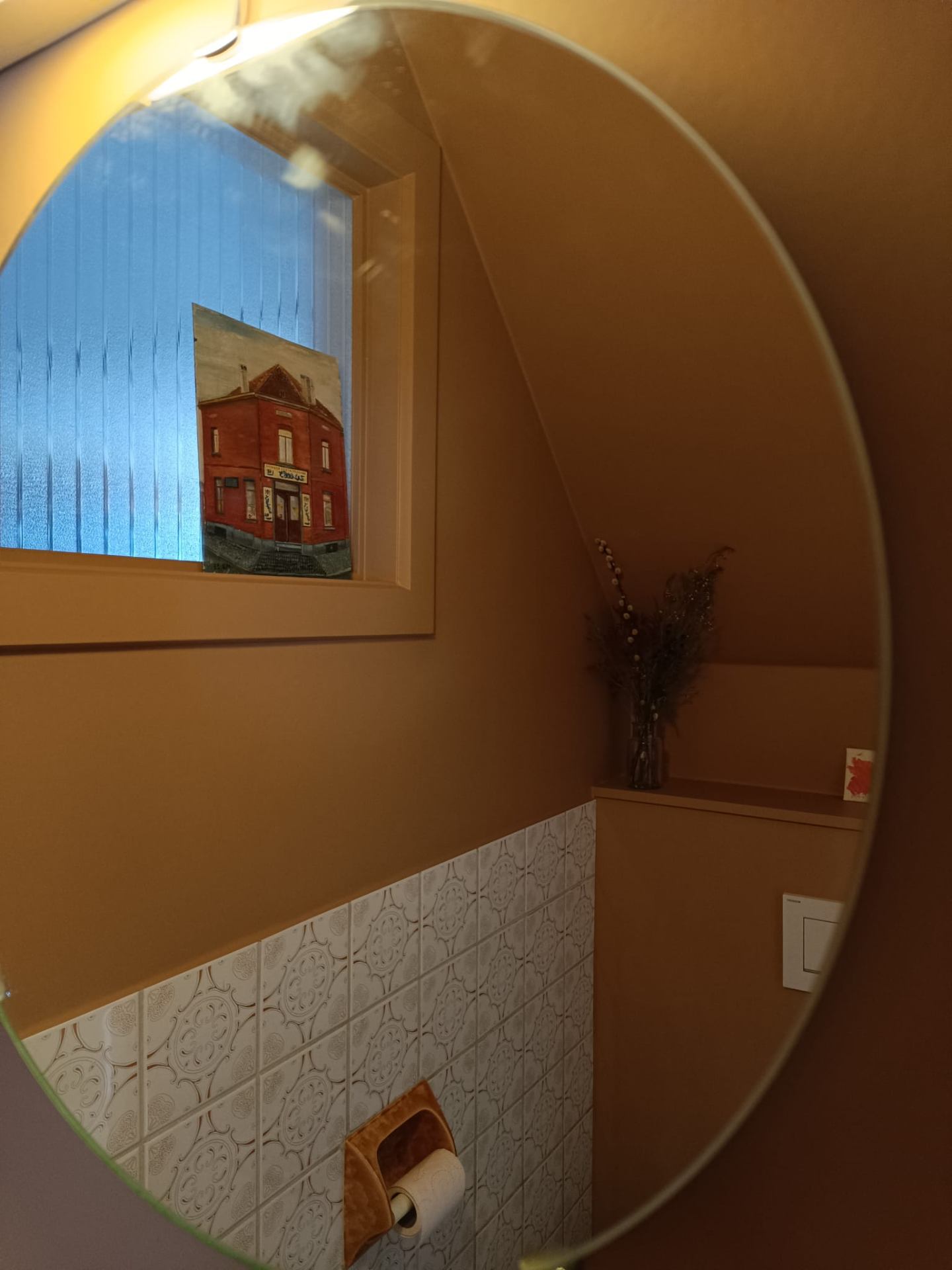Toilet met okergele wand en ronde spiegel