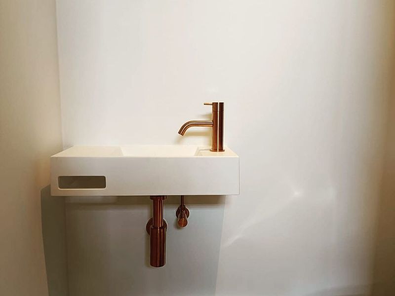 Badkamer met minimalistische wastafel en koperen kraan