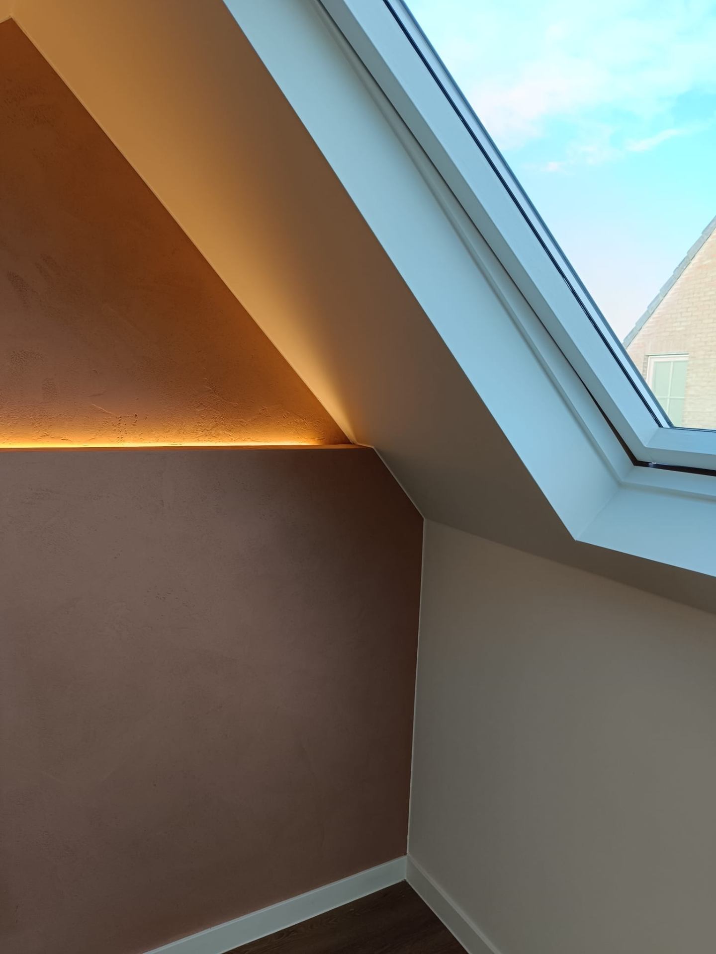 Zolder met leemstuc wand en dakraam met uitzicht
